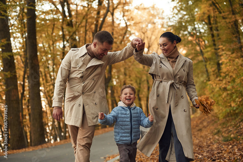 Running, having fun. Happy family are together in the autumn forest near the road