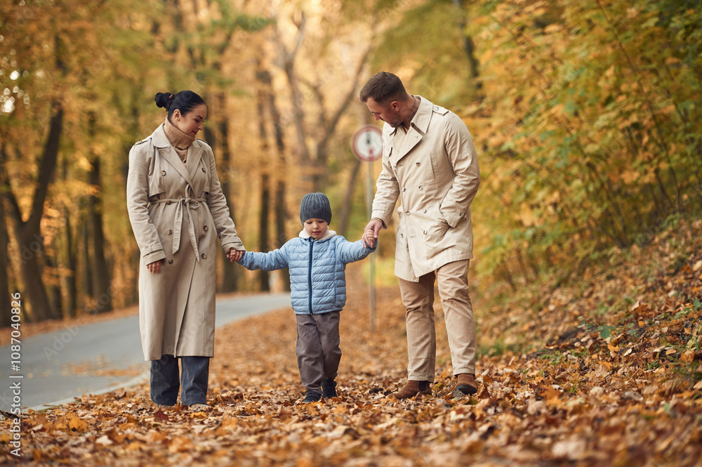 Fototapeta premium Having fun. Happy family are together in the autumn forest near the road