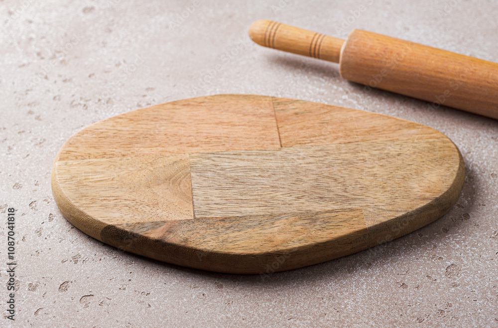 Empty wooden cutting board and a wooden rolling pin on a beige stone table, mockup for design Empty wooden cutting board and a wooden rolling pin on a beige stone table, mockup for design