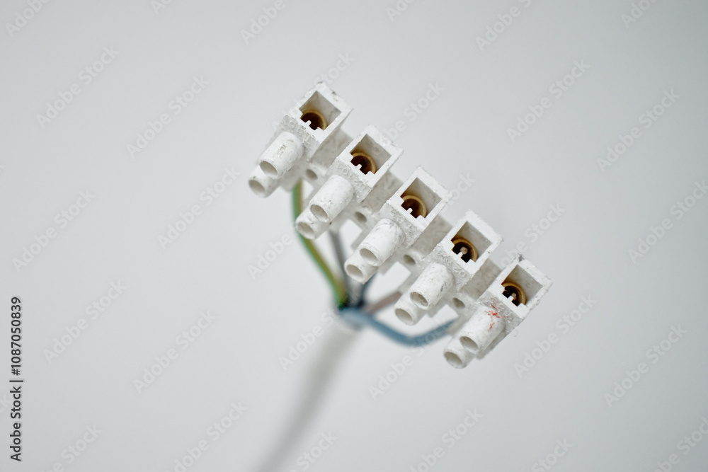Close-up of electrical wires extending from white wall. Electrical work during apartment renovation. Electricity cable in new apartment Close-up of electrical wires extending from white wall. Electrical work during apartment renovation. Electricity cable in new apartment