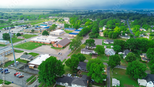 Traditional red brick buildings, residential houses in historic small-town USA of Checotah, McIntosh County, Oklahoma, churches, schools, large houses with vacant land, lush green trees, aerial photo