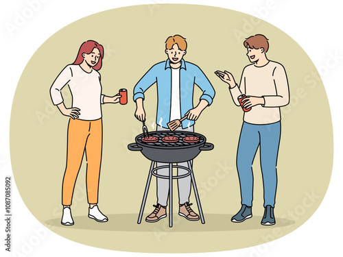BBQ party with cheerful friends drinking beer and grilling meat on grill in park or in backyard of house. Happy people celebrating start of summer vacation and cooking beef meat on BBQ coals