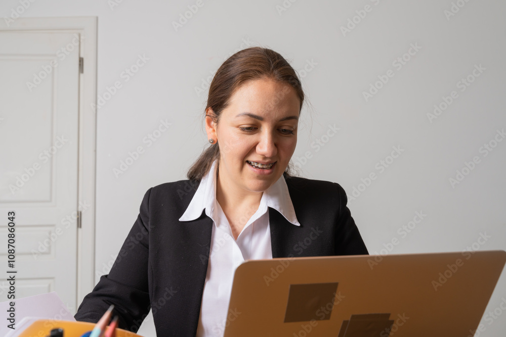 Young businesswoman with braces looks at her laptop screen. Young businesswoman with braces looks at her laptop screen.