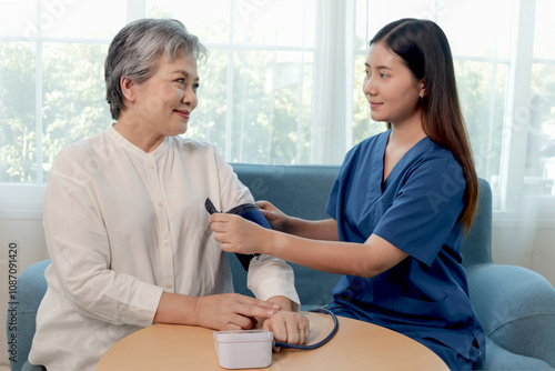 Female doctor measures arterial blood pressure of Asian senior woman. Nurse checking retirement grandma during examination. Happy mature receive checkup and advice from medical staff. elderly homecare