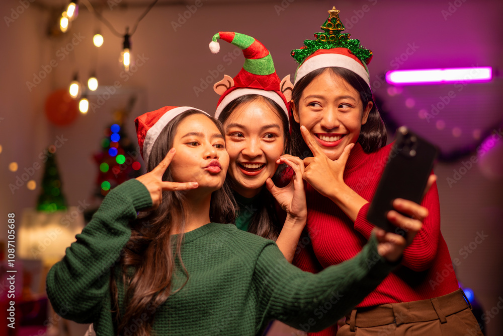 Three women are posing for a picture with Christmas hats and a cell phone Three women are posing for a picture with Christmas hats and a cell phone