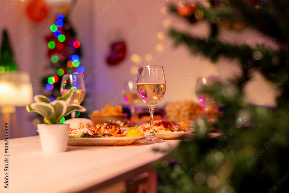 A table with a Christmas tree in the background and a glass of wine A table with a Christmas tree in the background and a glass of wine