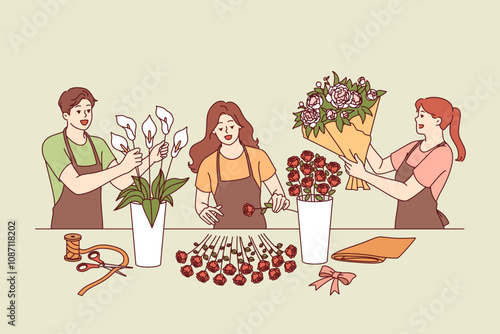 Flower shop employees collect festive bouquets for wedding or holiday party decoration. Man and two women working in flower shop create decorations from roses and lilies for event arrangements.