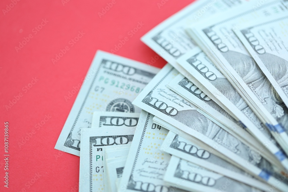 Big amount of hundred dollar bills in thick stack lies on bright red color paper background Big amount of hundred dollar bills in thick stack lies on bright red color paper background