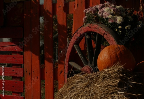 Autumn decoration with pumpkin, hay, flowers, painted boards, wicker basket, wooden wagon wheel photo