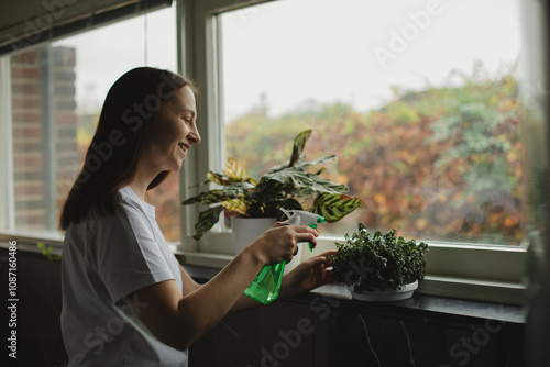 Young woman at home watering plant. Home gardening.Hobby concept. Concept, Save the planet photo