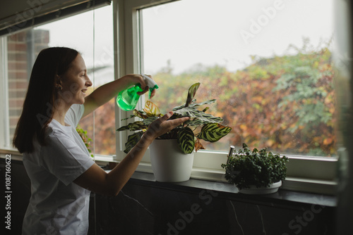 Young woman at home watering plant. Home gardening.Hobby concept. Concept, Save the planet photo