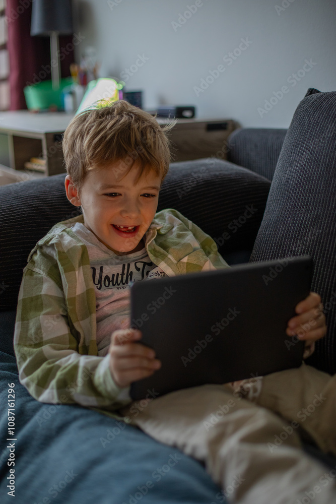 Boy using digital tablet while lying on bed at home