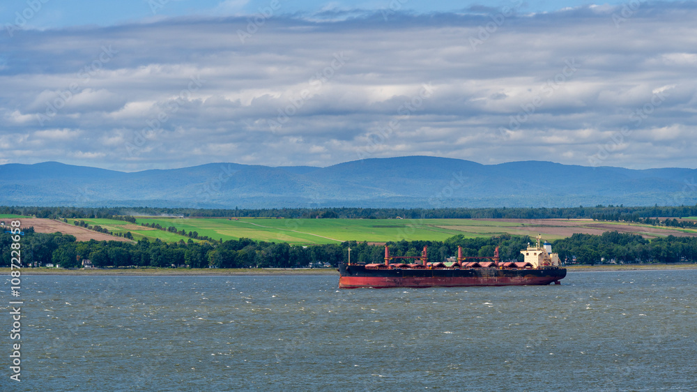 A cargo ship at anchor in front of crop fields A cargo ship at anchor in front of crop fields