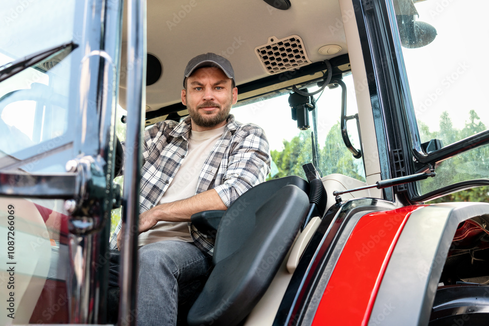 Adult Caucasian male farm worker driving tractor at farm. Adult Caucasian male farm worker driving tractor at farm.