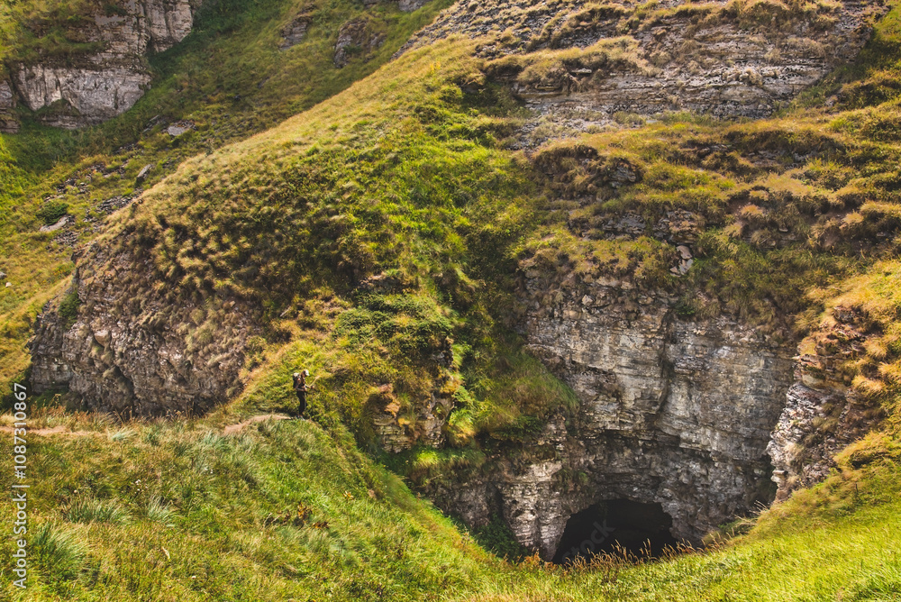 Small Person Walking Down Big Mountain with Cave