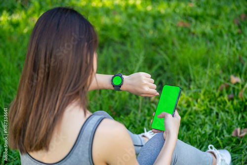 Green screen on Mobile and smartwatch - Asian Woman Checking Health Data on Smartphone and Smartwatch in Park photo