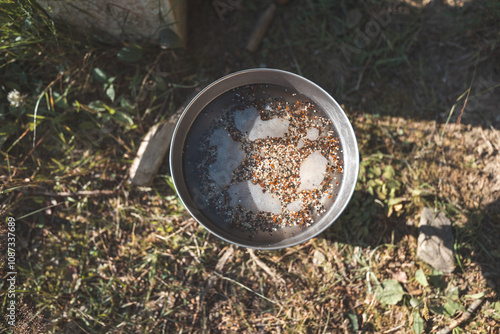 Wallpaper Mural Cooking quinoa outdoors in a portable pot with a spoon, surrounded by nature. A simple, healthy meal preparation that highlights outdoor cooking and sustainable living Torontodigital.ca