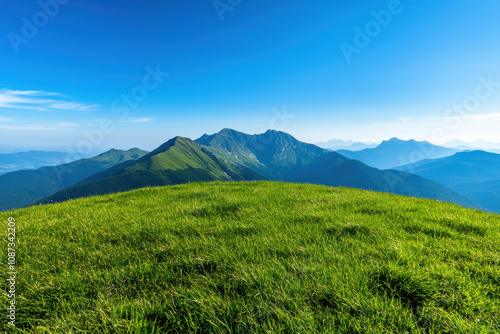 Stunning panoramic view of lush green mountains under a clear blue sky, showcasing nature's beauty and tranquility in a serene landscape.