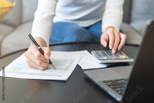 Deduction planning concept. Asian young woman hand using calculator to calculating balance prepare tax reduction income, cost budget expenses for pay money form personal Individual Income Tax Return.