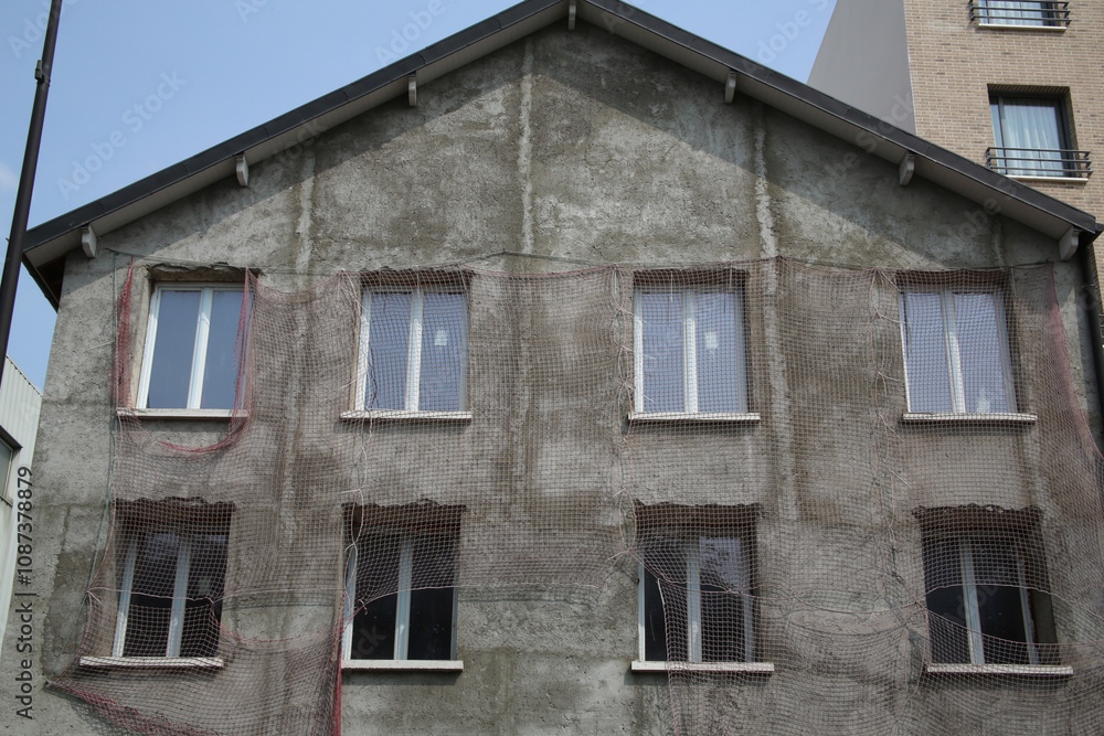 Obraz premium Filet de protection anti-chute sur la façade d'une maison en travaux