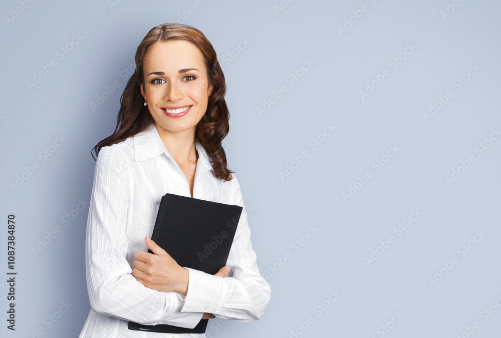 Portrait image of happy smiling business woman businesswoman, teacher, manager real estate agent hold black folder. Brunette hair girl wear white cloth. Isolated grey gray wall background. Ad concept Portrait image of happy smiling business woman businesswoman, teacher, manager real estate agent hold black folder. Brunette hair girl wear white cloth. Isolated grey gray wall background. Ad concept