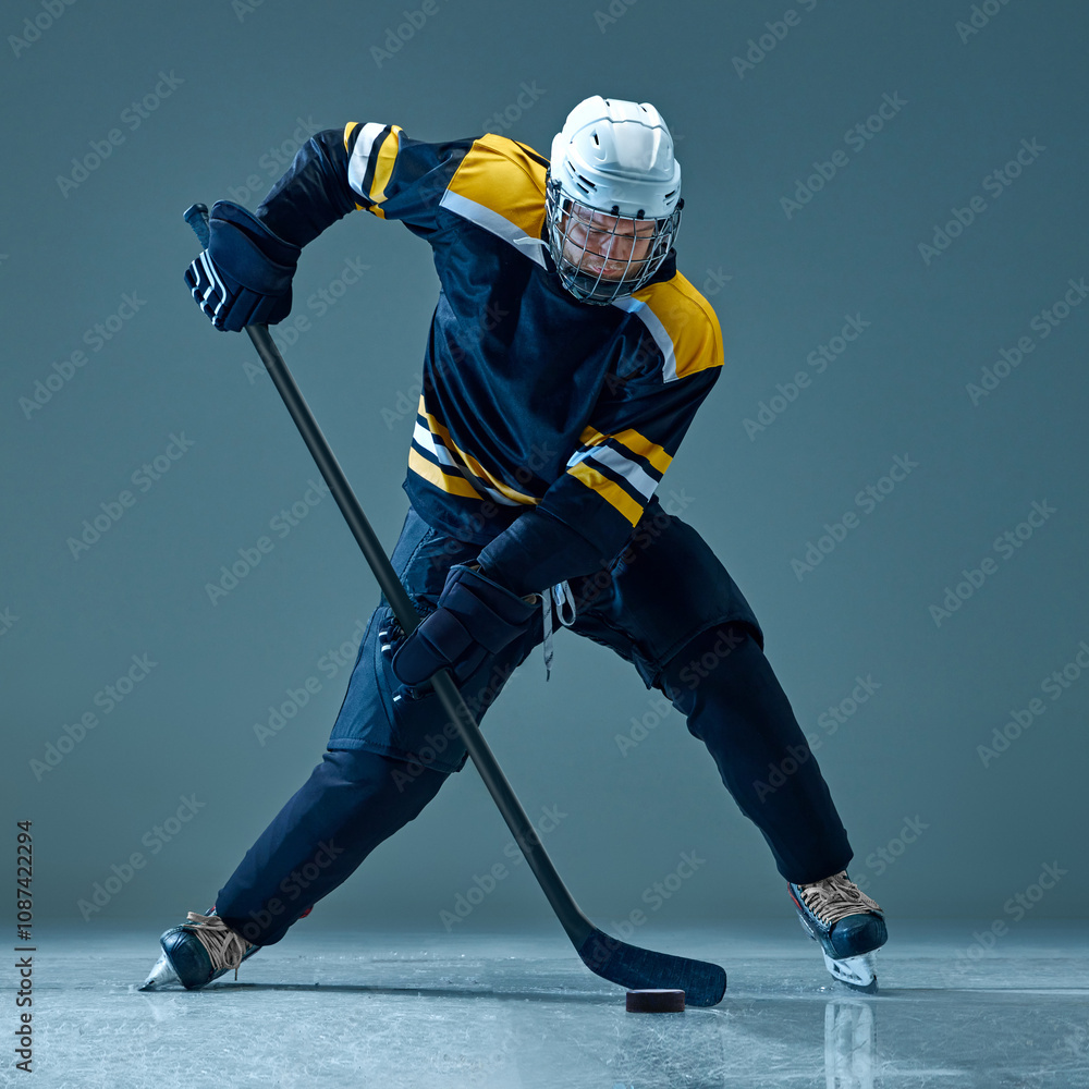 Focused man, ice hockey player captured in motion, powerfully skating across rink, holding stick. Intense game. Concept of sport, game, tournament, action, competition Focused man, ice hockey player captured in motion, powerfully skating across rink, holding stick. Intense game. Concept of sport, game, tournament, action, competition