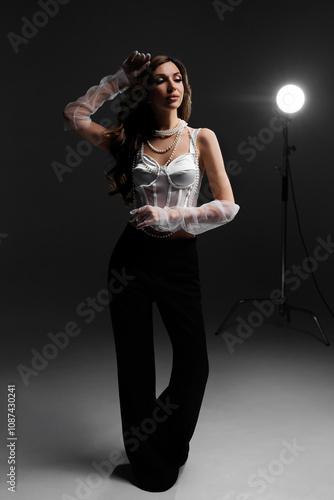 Portrait of a woman in a white blouse and with pearl beads in the spotlight in the studio. photo