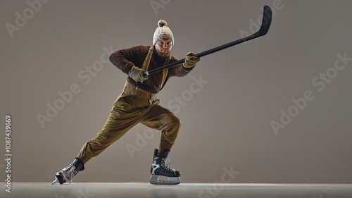 Sticker Bearded man, hockey player in retro outfit, wearing knitted hat and sweater, pants with suspenders, in motion with stick on studio background