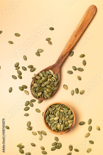 Fresh pumpkin seeds in wooden bowl and in spoon on beige background, top view flat lay. Organic eco healthy seeds, superfood, diet food, healthy vegetarian food. Smoothie Ingredient 