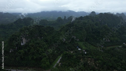 Chumpon Thailand.A mountain range with a cloudy sky and a small village in the distance