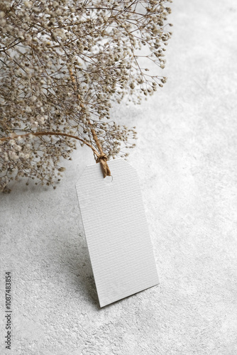 Blank price tag card mockup with dry gypsophila flowers decor, white label mock up with copy space