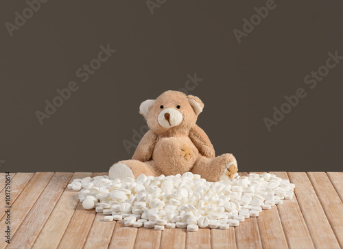 Teddy bear behind pile of tablets photo