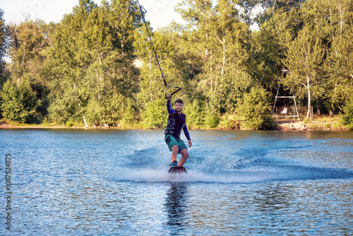 Canvas Print A man wakeboarding on a lake on summer day in a life  jacket