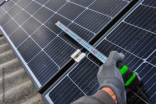 solar panel installation. a master takes measurements with a tape measure during the installation of solar panels. the process of installing solar panels on a roof