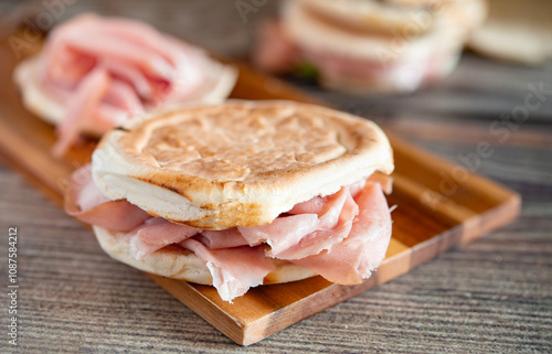 Tigelle with mortadella and rocket on wooden cutting board