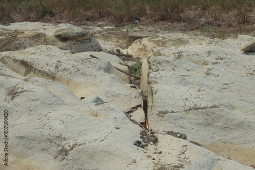 A dry riverbed showcases a unique texture of white, eroded rocks with natural indentations and pebbles scattered between