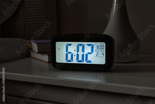 A digital alarm clock shows 602 PM in a cozy bedroom, creating an inviting atmosphere