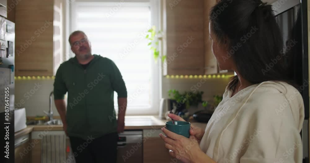 Close-up of a woman smiling while holding a coffee mug, man in the blurred background leaning on the kitchen counter, casual moment in a modern home Close-up of a woman smiling while holding a coffee mug, man in the blurred background leaning on the kitchen counter, casual moment in a modern home