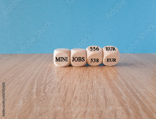 Symbol for the raise of the income limit for tax free 'mini jobs' in Germany from 538 Euro to 556 Euro in 2025 on wooden cubes. Beautiful blue background. Business concept. photo