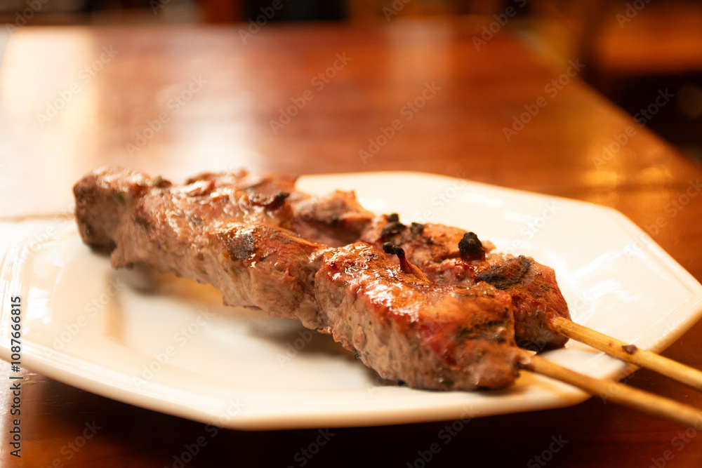 beef filet mignon skewer in close-up macro shot on plate under wooden table beef filet mignon skewer in close-up macro shot on plate under wooden table
