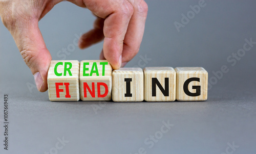 Finding or creating symbol. Businessman turns wooden cubes and changes words Finding to Creating. Beautiful grey table grey background copy space. Business creating or finding concept.