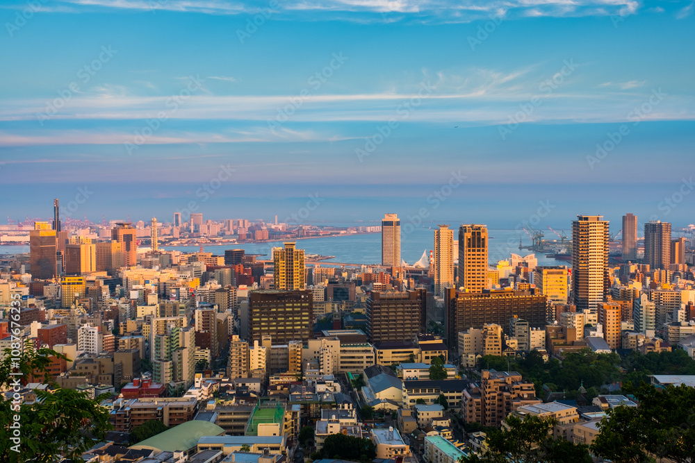 Obraz premium Kobe, Japan. Aerial view of downtown Kobe, Japan at sunset. Time-lapse of the colorful sky with boats at the harbor and numerous skyscrapers, zoom in 