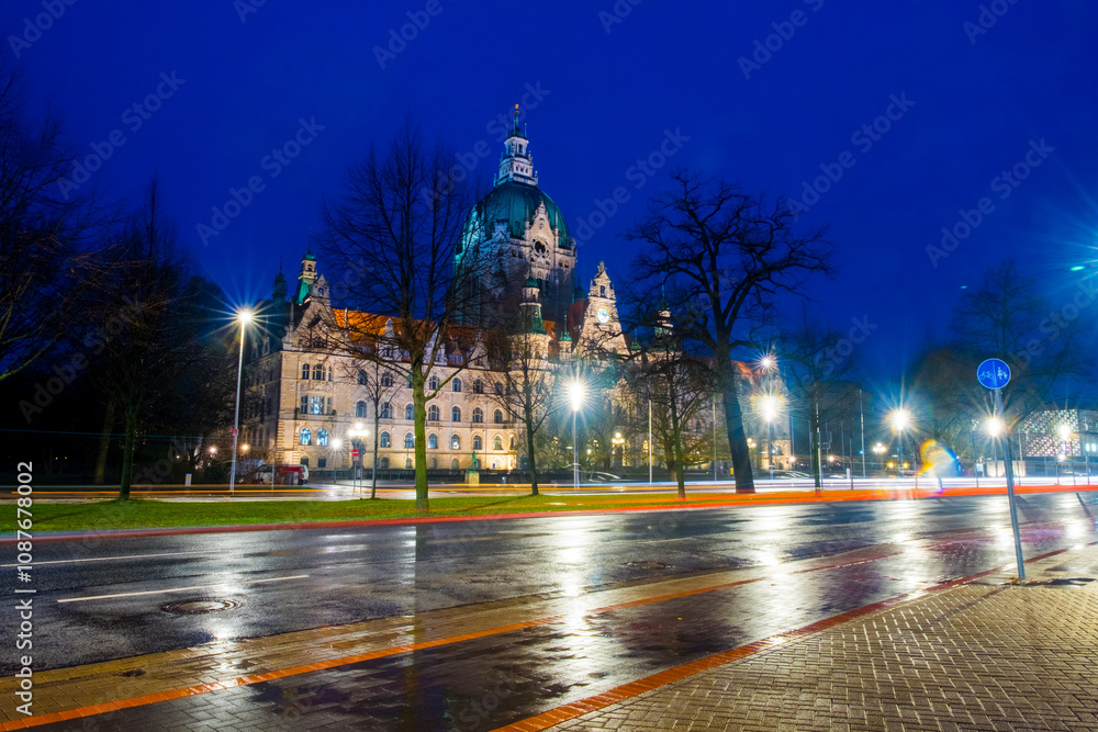 Obraz premium Hanover, Germany. The New Town Hall in Hanover, Germany at sunrise. Time-lapse of the road and illuminated landmark with cloudy sky in the morning