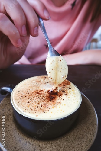 Close-up of a person enjoying traditional Vietnamese egg yolk coffee, known as 