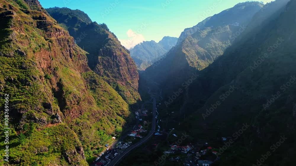 Narrow valley located among the high mountains. City crossed by the highway is among the rocks. Madeira, Portugal from top view. Narrow valley located among the high mountains. City crossed by the highway is among the rocks. Madeira, Portugal from top view.