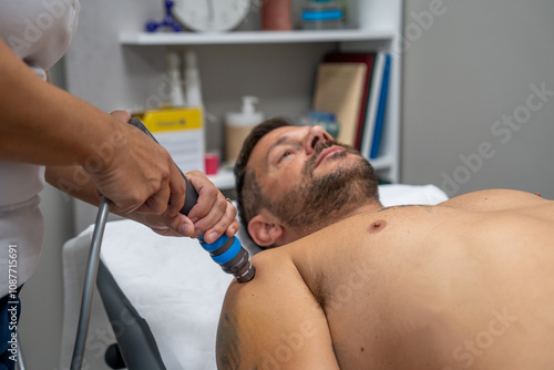 Obraz na płótnie Expert administers targeted shockwave therapy to treat a man's shoulder pain w salonie