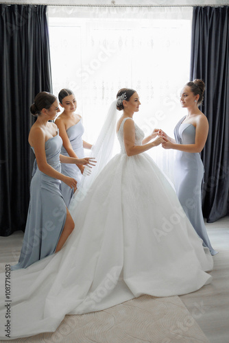 A bride is getting ready for her wedding with her bridesmaids. The bride is wearing a white dress and the bridesmaids are wearing blue dresses