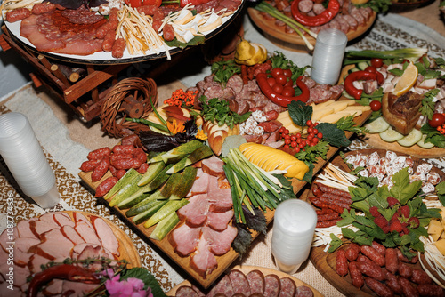 A table full of food with a variety of meats, vegetables, and cheeses. The table is set for a party or gathering