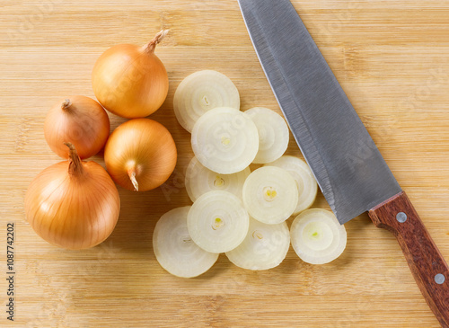 A top down view of chopped yellow onion on a cutting board. Half an onion and a whole yellow onions on a cutting board, top view. photo