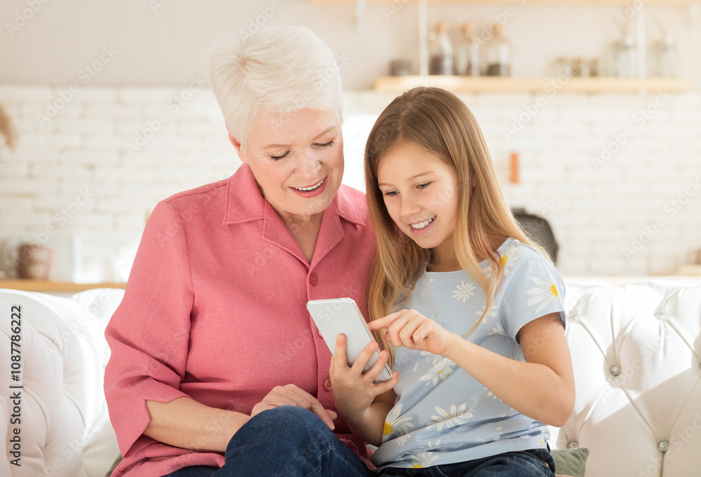 Family pastimes. Mature woman playing video games on smartphone with her granddaughter at home Family pastimes. Mature woman playing video games on smartphone with her granddaughter at home